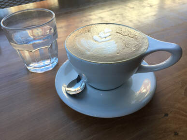 Photo of cappuccino and a glass of water on wooden table